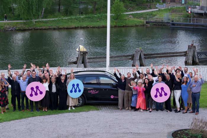 Hela laget bakom Moderaterna i Trollhättan vinkar glatt vid kanalen, med M-symboler i händerna