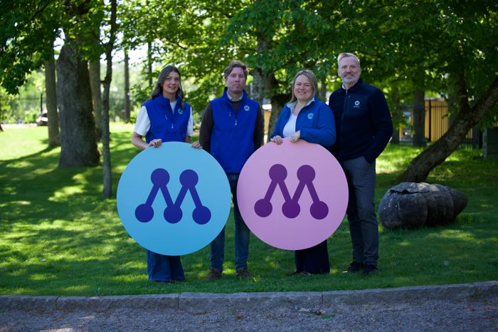 Fyra kandidater i parken håller upp två stora M-symboler